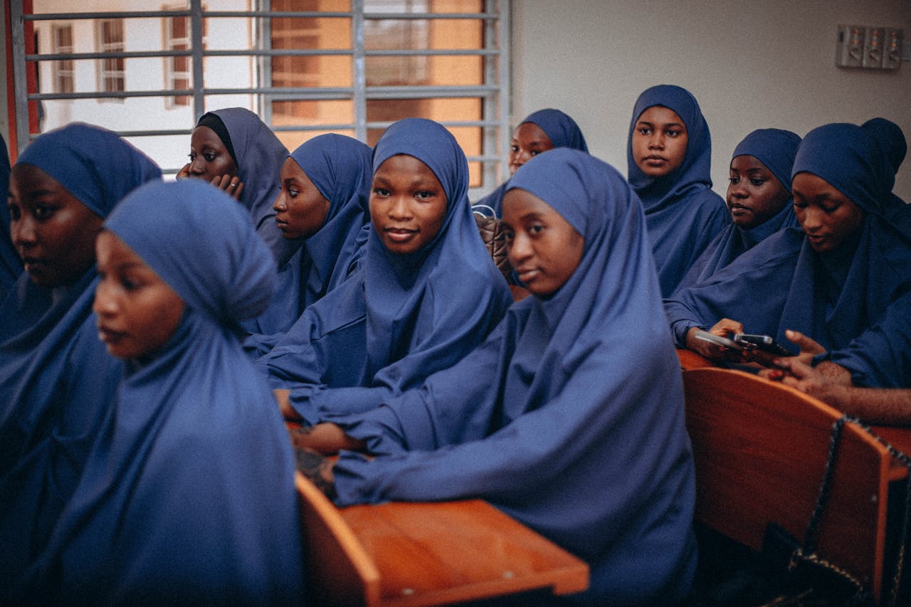 Group of young students in blue hijabs attending class, reflecting focus and education.