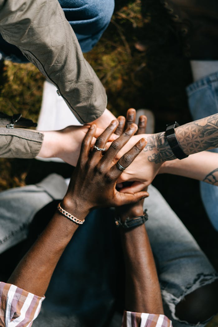 A group of diverse individuals placing their hands together in unity, symbolizing teamwork and collaboration.